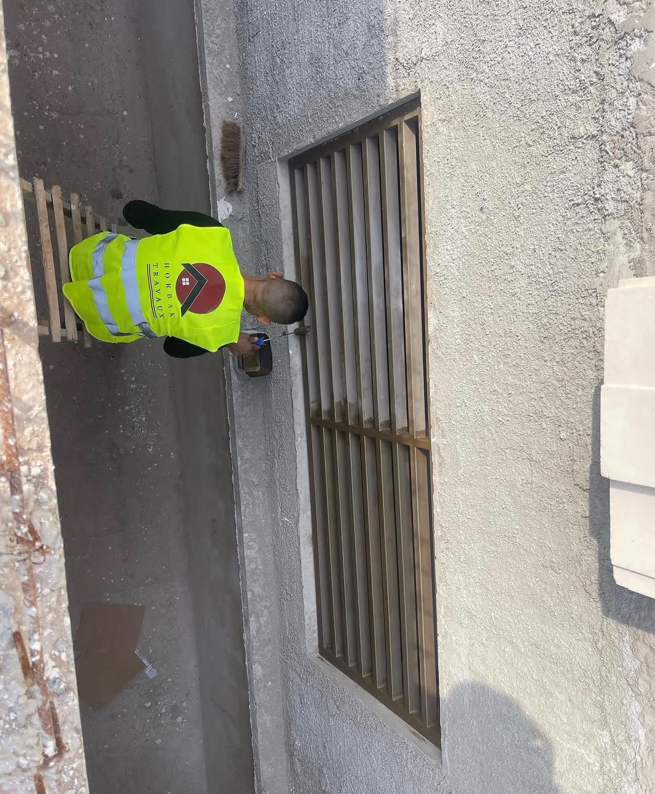 Mise en place d’une grille métallique en façade. Un aperçu du travail de fixation sur site.